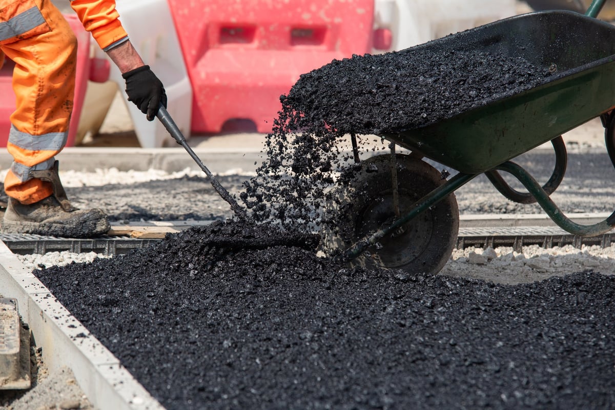 Team of road workers repairing road surface with hot asphalt