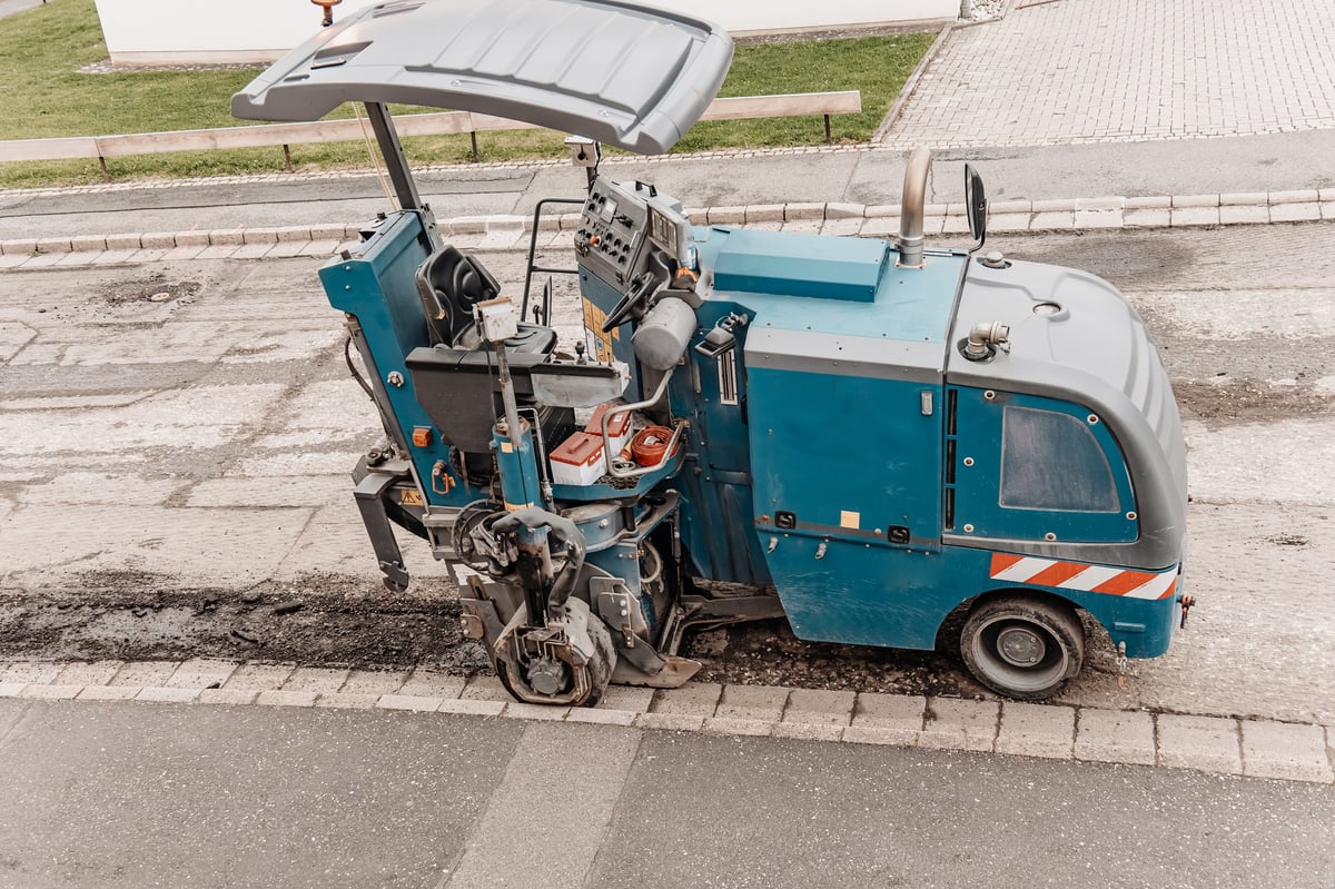 Road milling machine removing old asphalt near a curb