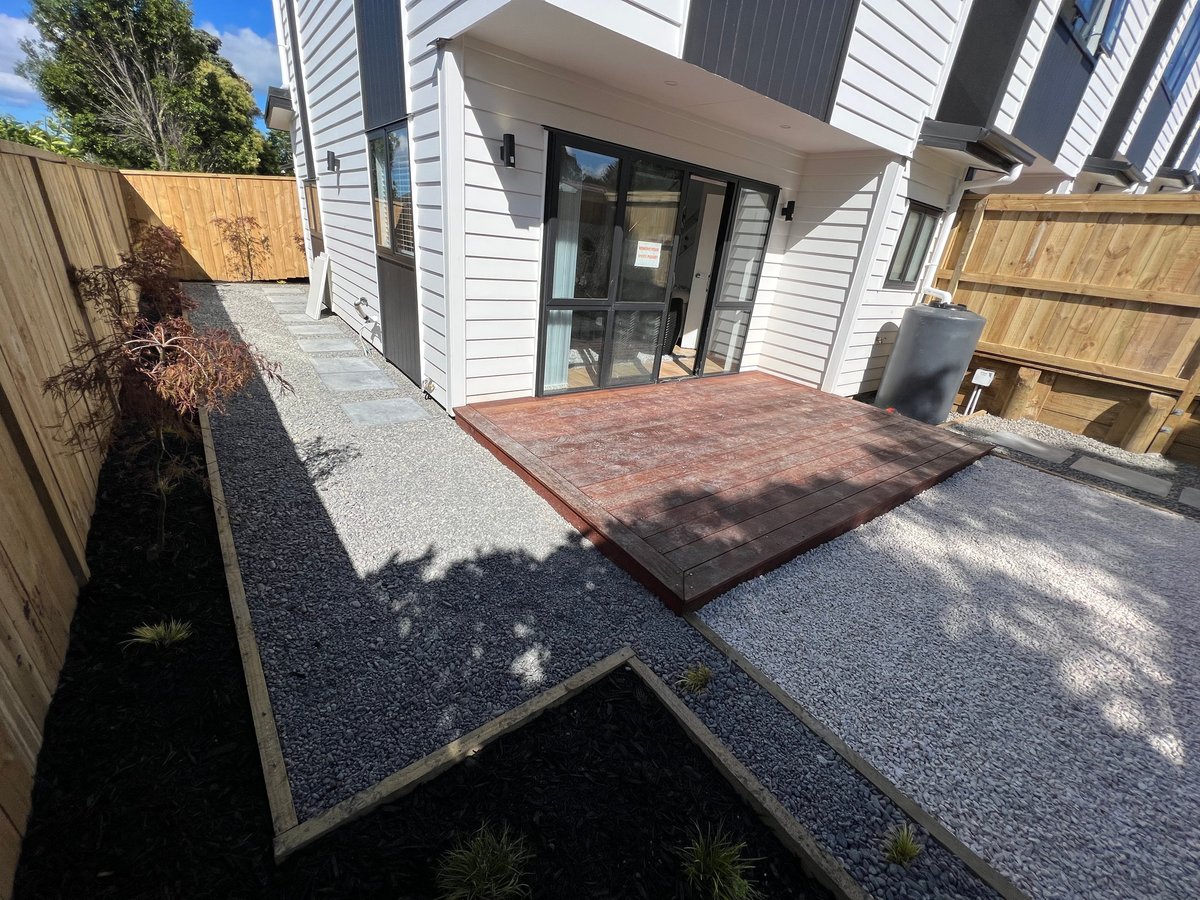 Modern home exterior with gravel courtyard, red brick patio, wooden fences, and contemporary architecture