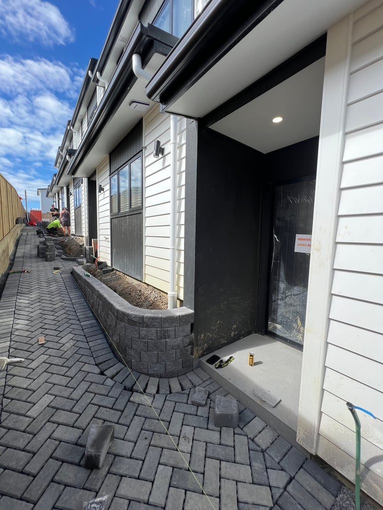 Modern row houses with white siding and black trim along a paved alleyway on a sunny day