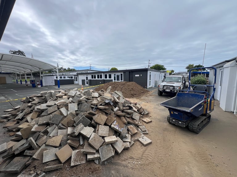 Industrial recycling yard with large pile of concrete blocks, equipment, and storage buildings under cloudy sky