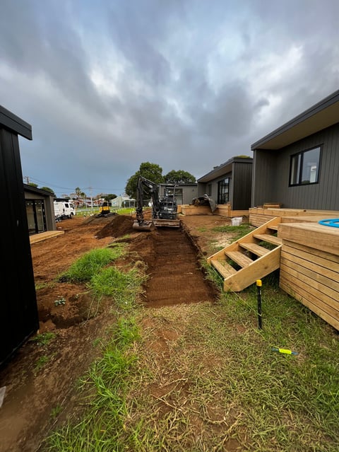 Backyard construction site with wooden deck stairs, metal modular homes under cloudy sky