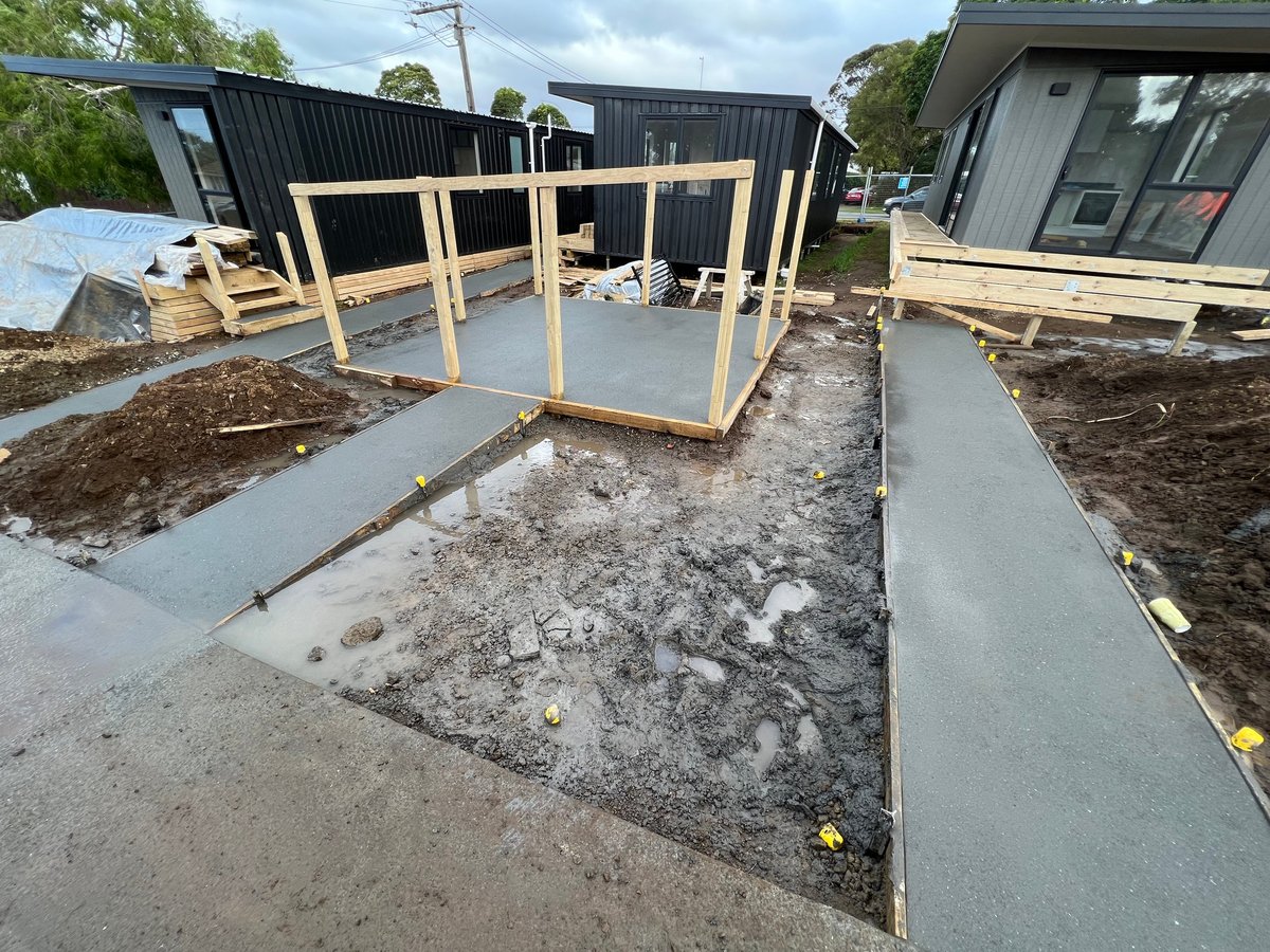 New building construction with wooden frame, concrete foundation, and framing structure in early stages of development