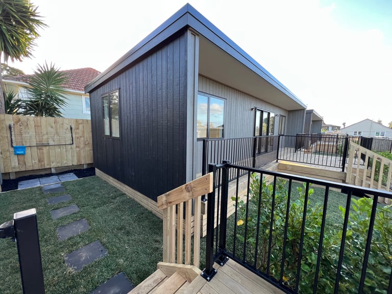 Modern black and white residential building with deck and stairs in suburban neighborhood