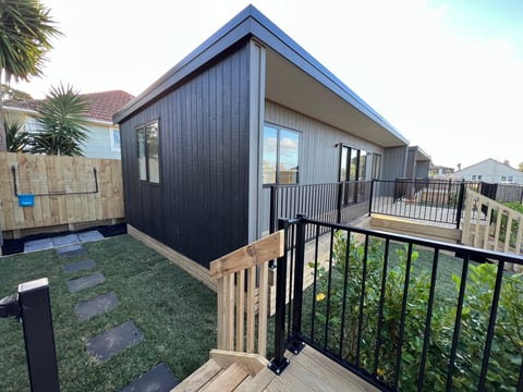 Modern black and white residential ADU with deck and metal railing overlooking residential neighborhood