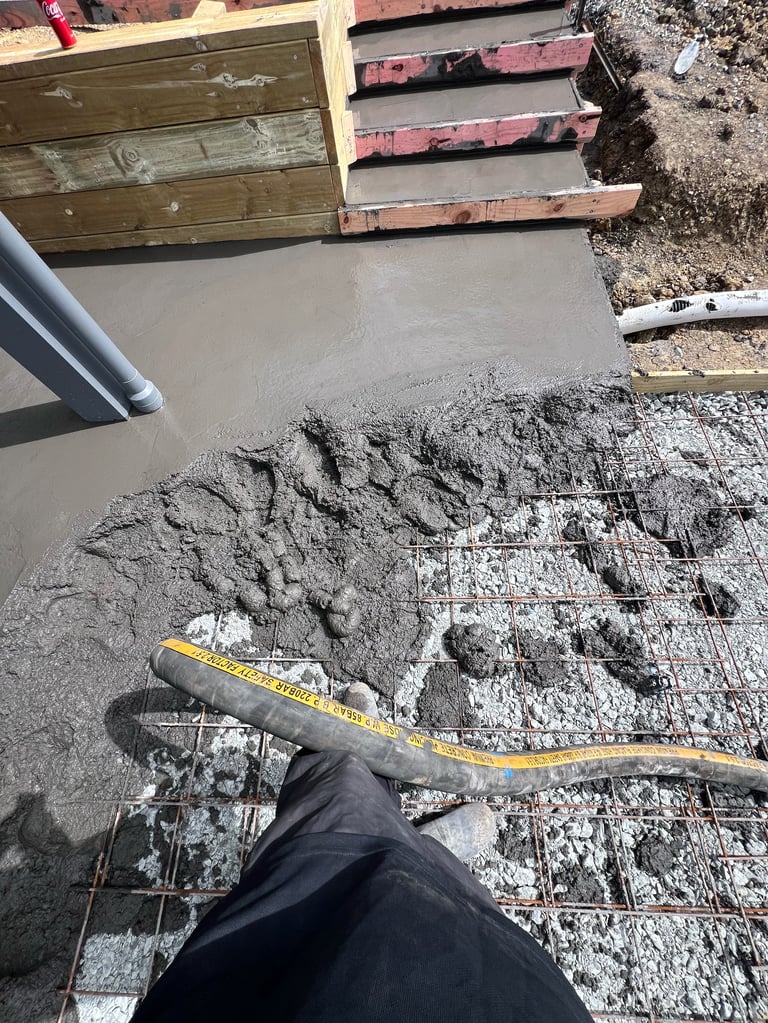 Construction worker measuring freshly poured concrete foundation with tape measure on construction site